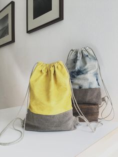 two drawstring bags sitting next to each other on a white counter in front of pictures