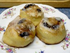 three pastries sitting on top of a plate covered in icing and blueberries