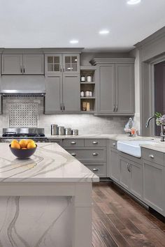 a large kitchen with gray cabinets and marble counter tops