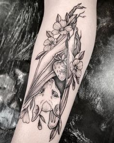 a woman's leg with a bat and flowers on it, in black and white