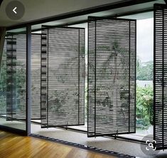 an open room with wooden flooring and sliding glass doors that have black slats on them