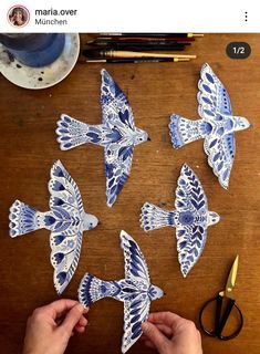 someone is cutting out blue and white paper butterflies