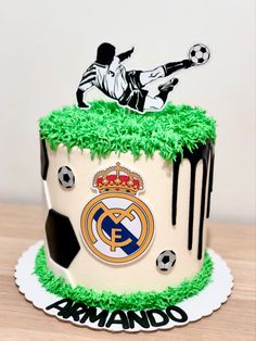 a birthday cake decorated with soccer balls and the logo of real madrid is on display