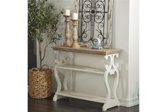 a white console table with two candles and a potted plant