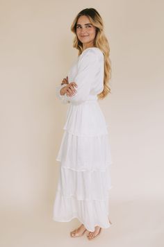 Step into something special with The White: Whitney. This exquisitely designed maxi-length white temple dress is made from a luxe silky material and features fully lined long sleeves, pockets! and a high rounded neck with a keyhole button closure. The double elastic waistband lends a romantic touch, and the tiered ruffle skirt seals the deal. Ready to step up your temple dress game? Look no further! Details Temple dress White dress Maxi-length Long sleeves Fully lined Pockets! High rounded neck White Temple Dress, Modest White Dress, Lds Temple Dress, White Temple, Temple Dress, Tiered Ruffle Skirt, Game Dresses, The Deal, Cream Dress