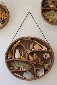 three clay pots are hanging on the wall with plants and rocks in them, along with other decorative items