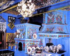 an artisticly decorated kitchen with blue walls and ceiling, has many plates on the counter