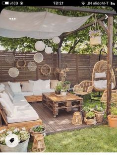 an outdoor living area with wicker furniture and hanging plants on the side of it