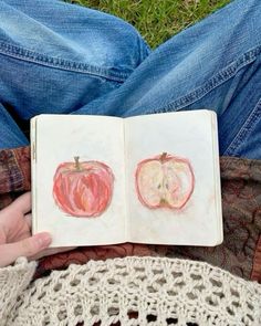 someone is holding an open book with drawings of two apples and one apple on it