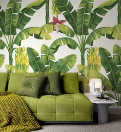 a green couch sitting in front of a wall with banana leaves on it's side