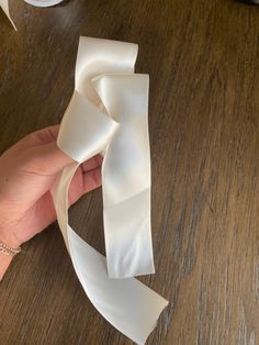 a person holding a white ribbon on top of a wooden table