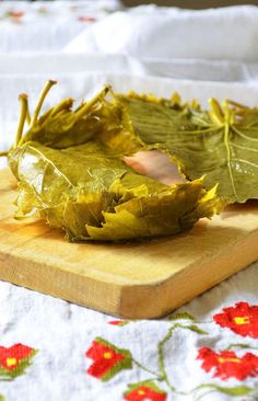 a wooden cutting board topped with leaves on top of a table