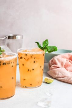 two glasses filled with lemonade and mint sprinkles next to a tea pot