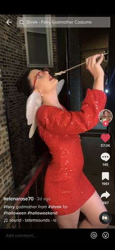 a woman in a red sequin dress is holding a stick and looking at the camera