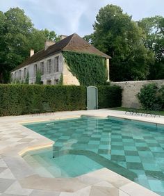 an empty swimming pool in front of a large house with ivy growing on the walls