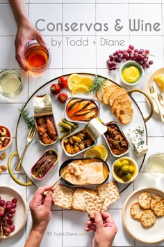 people are eating and drinking wine at a table full of food, including crackers