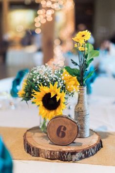 sunflowers and baby's breath in a vase on a wood slice table number