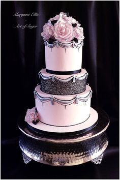 a three tiered wedding cake with pink flowers on the top and black trimmings