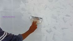 a man is painting a wall with white paint and peeling off the plaster on it