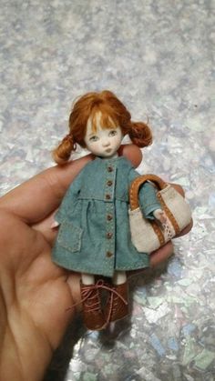 a hand holding a doll with a purse