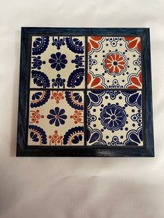 three tiles are in a blue frame on a white sheet with orange and blue designs