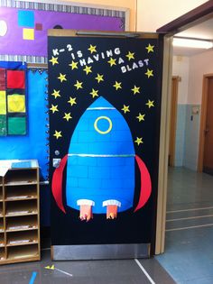 a blue rocket ship made out of legos on the floor in front of a classroom door