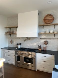 a stove top oven sitting inside of a kitchen next to open shelving units and wooden shelves