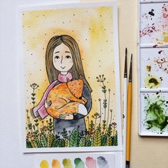 a drawing of a girl holding a cat in her arms with watercolor paints on the table next to it