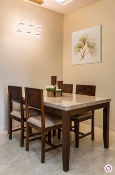 a dining room table with chairs and a painting hanging on the wall behind it,