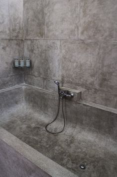 a bathroom with a shower head, soap dispenser and toilet paper