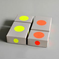 three boxes with different colored dots on them sitting next to each other in front of a gray background