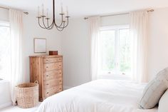 a bedroom with a bed, dresser and two windows