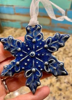 a blue snowflake ornament is being held by someone's hand