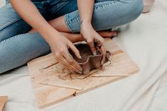 a woman is sitting on the floor working on something with wood shavings around her