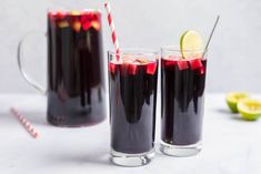 two glasses filled with red liquid and lime slices