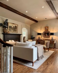 a living room filled with furniture and a fire place next to a wooden floored staircase