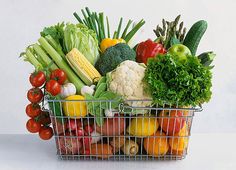 a basket filled with lots of different types of fruits and veggies on top of a table