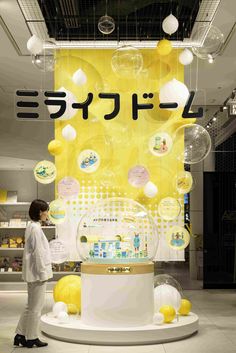 a woman standing in front of a display case with yellow balloons hanging from the ceiling