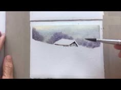 someone is drawing a house in the snow with watercolor pencils on white paper