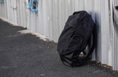 a black backpack leaning against a wall