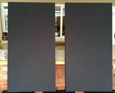 two black speakers sitting next to each other in front of a brick wall