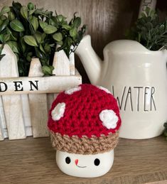 a crocheted mushroom hat sitting on top of a table next to a potted plant