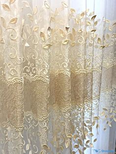 curtains with gold leaves on them are hanging in front of a white curtain that is open