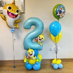 some balloons are in the shape of numbers with cartoon characters on them and one balloon is shaped like a shark