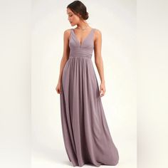 a woman in a long purple dress is looking back at the camera and she has her hands on her hips