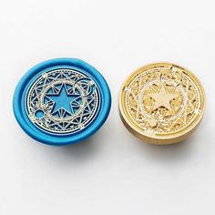 two different colored metal buttons on a white surface, one is gold and the other is blue