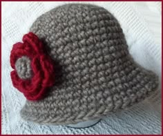 a crocheted hat with a red flower on it