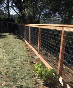 the fence is made of wood and has wire on top, along with grass in the yard