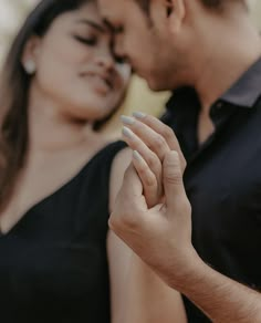 a man and woman are holding hands close to each other as they look into the distance