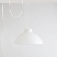 a white lamp hanging from the ceiling in a room with no one around it,